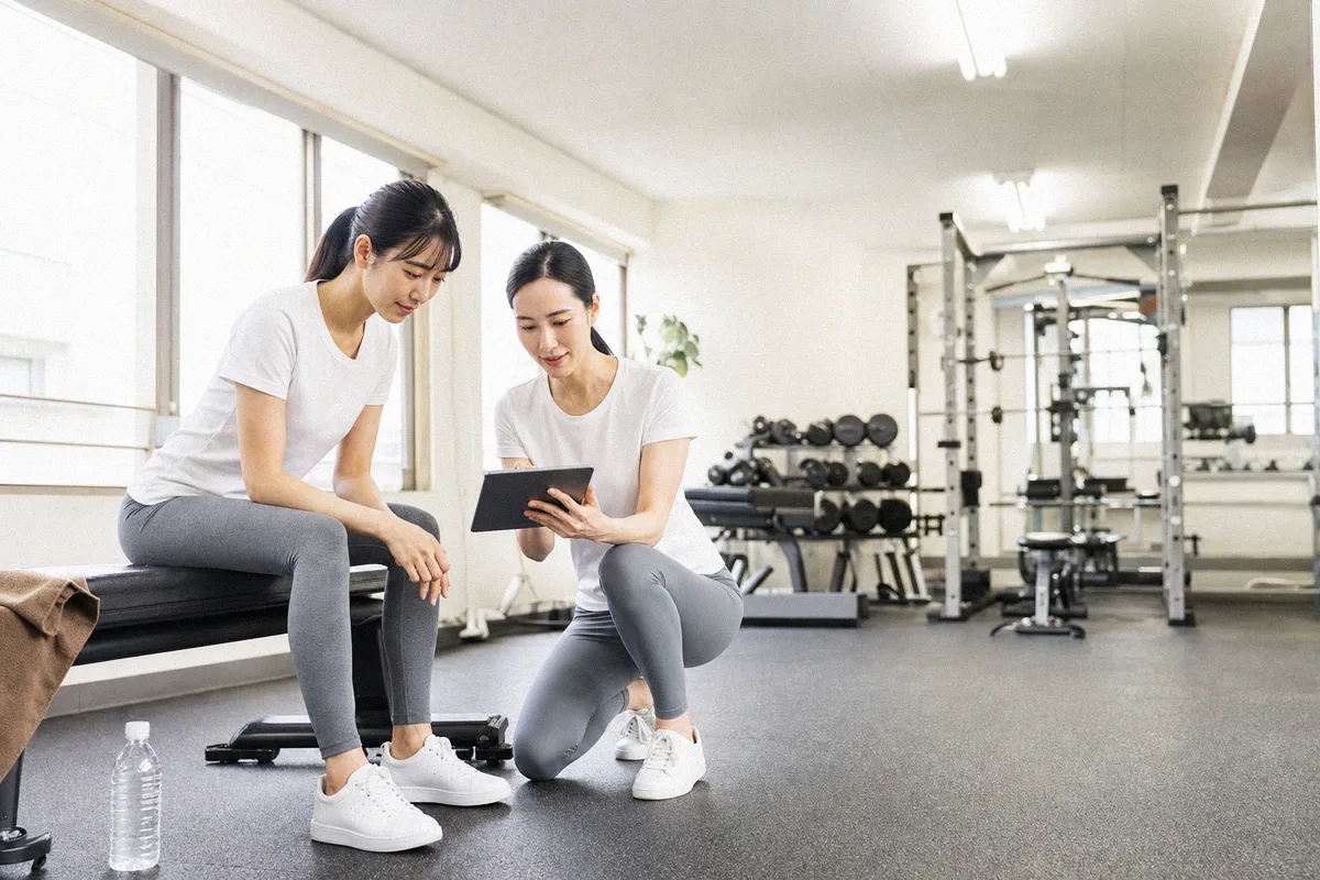タブレットを見ながらトレーニング計画の説明を受ける利用者とトレーナー