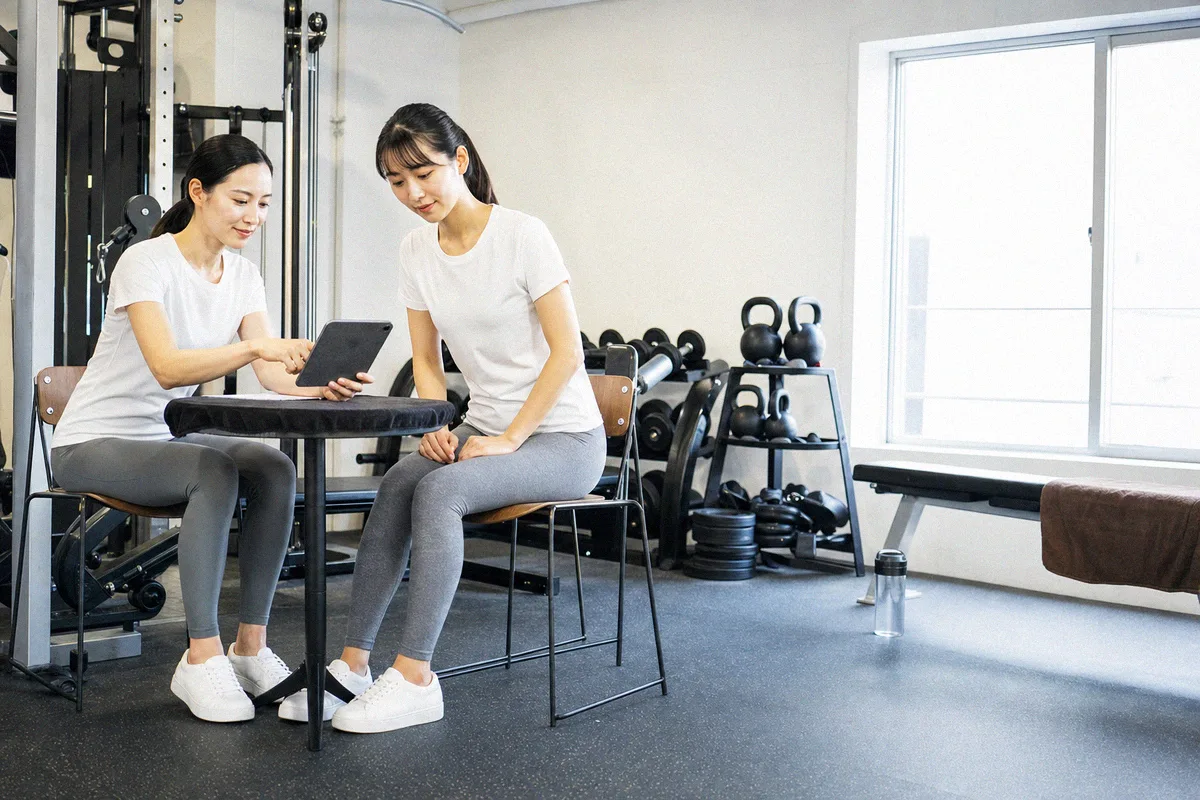 タブレットを見ながらトレーニング計画の説明を受ける利用者とトレーナー