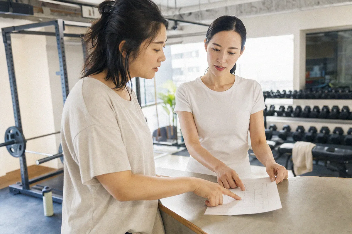 テーブル越しに料金や進め方について話すトレーナーと利用者