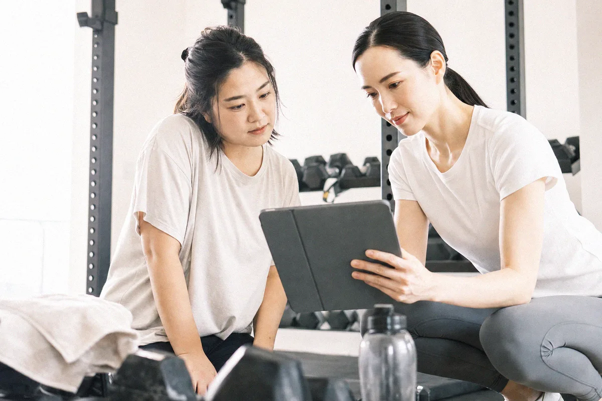 タブレットを見ながらトレーニング計画の説明を受ける利用者とトレーナー