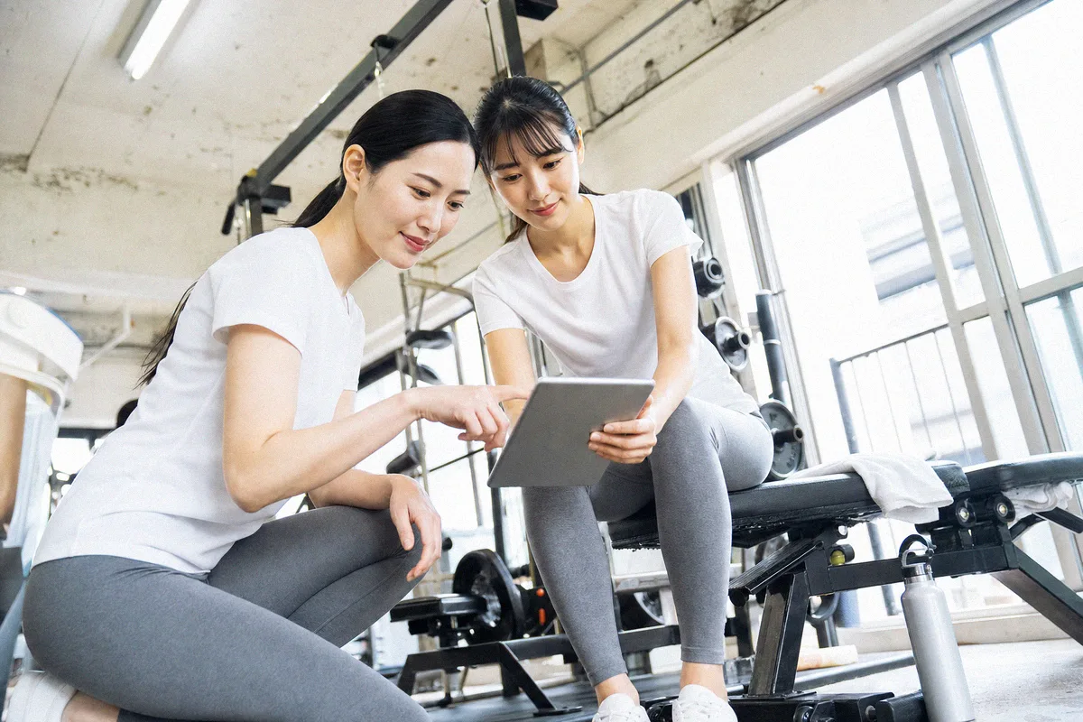 ベンチに並んで腰かけ、タブレットの画面をのぞき込む2人