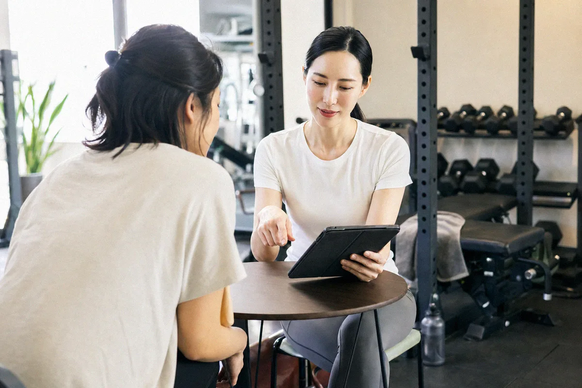 テーブル越しに料金や進め方について話すトレーナーと利用者