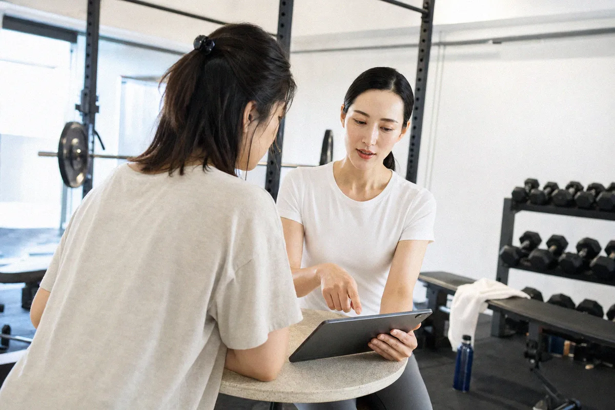 タブレットを見ながらトレーニング計画の説明を受ける利用者とトレーナー