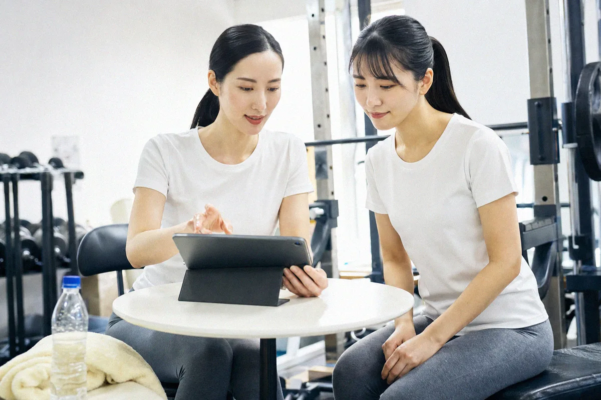 タブレットを見ながらトレーニング計画の説明を受ける利用者とトレーナー