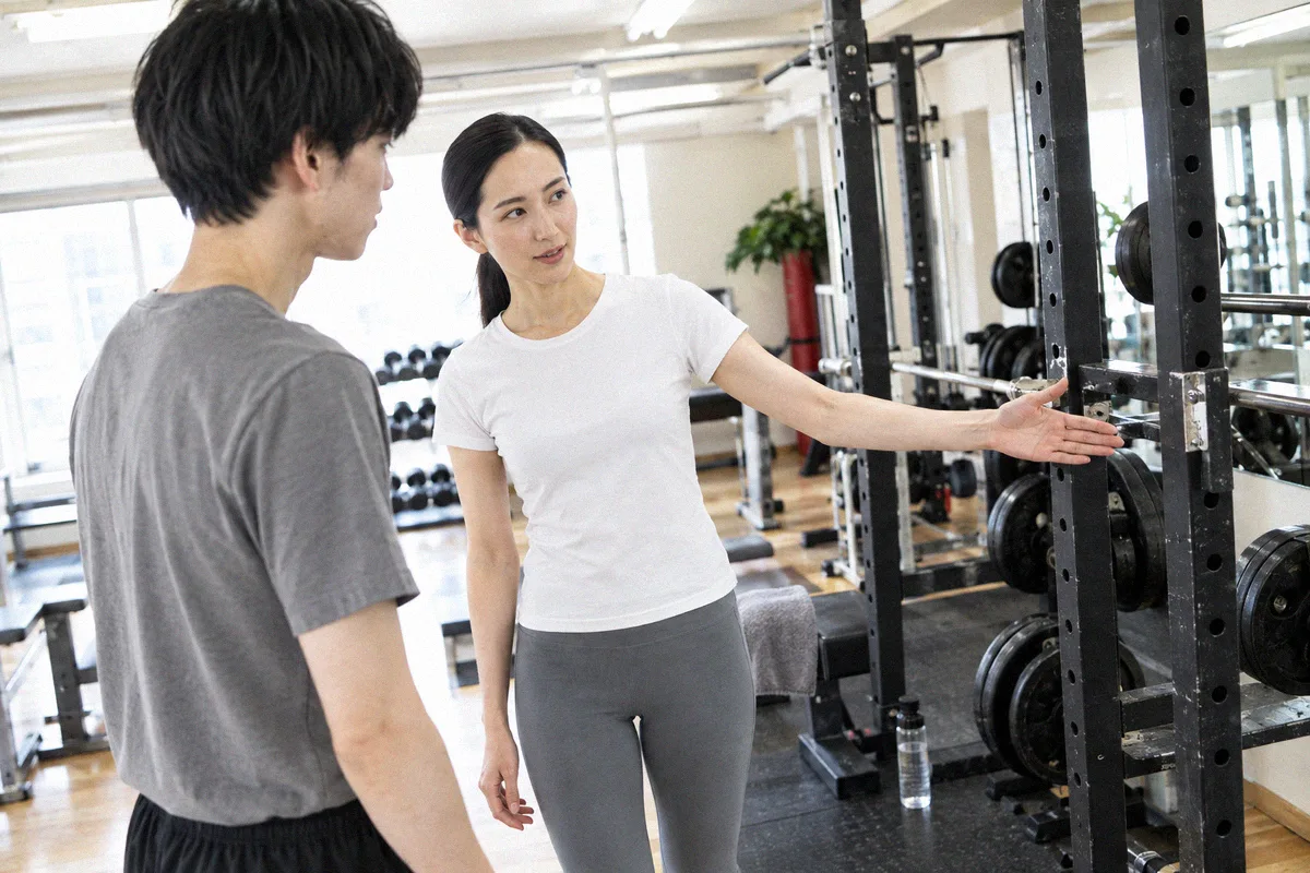 ラックを指して設備を案内するトレーナーと利用者