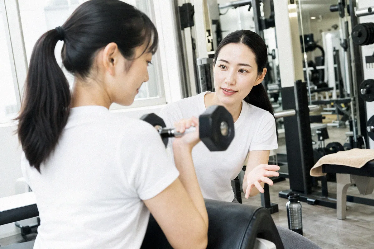 肘の角度を確認するトレーナーと、動作の途中で静止する利用者