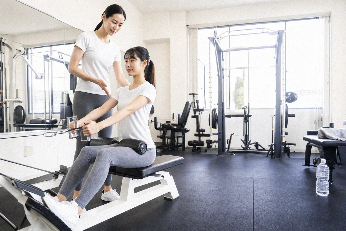 肘の角度を確認するトレーナーと、動作の途中で静止する利用者