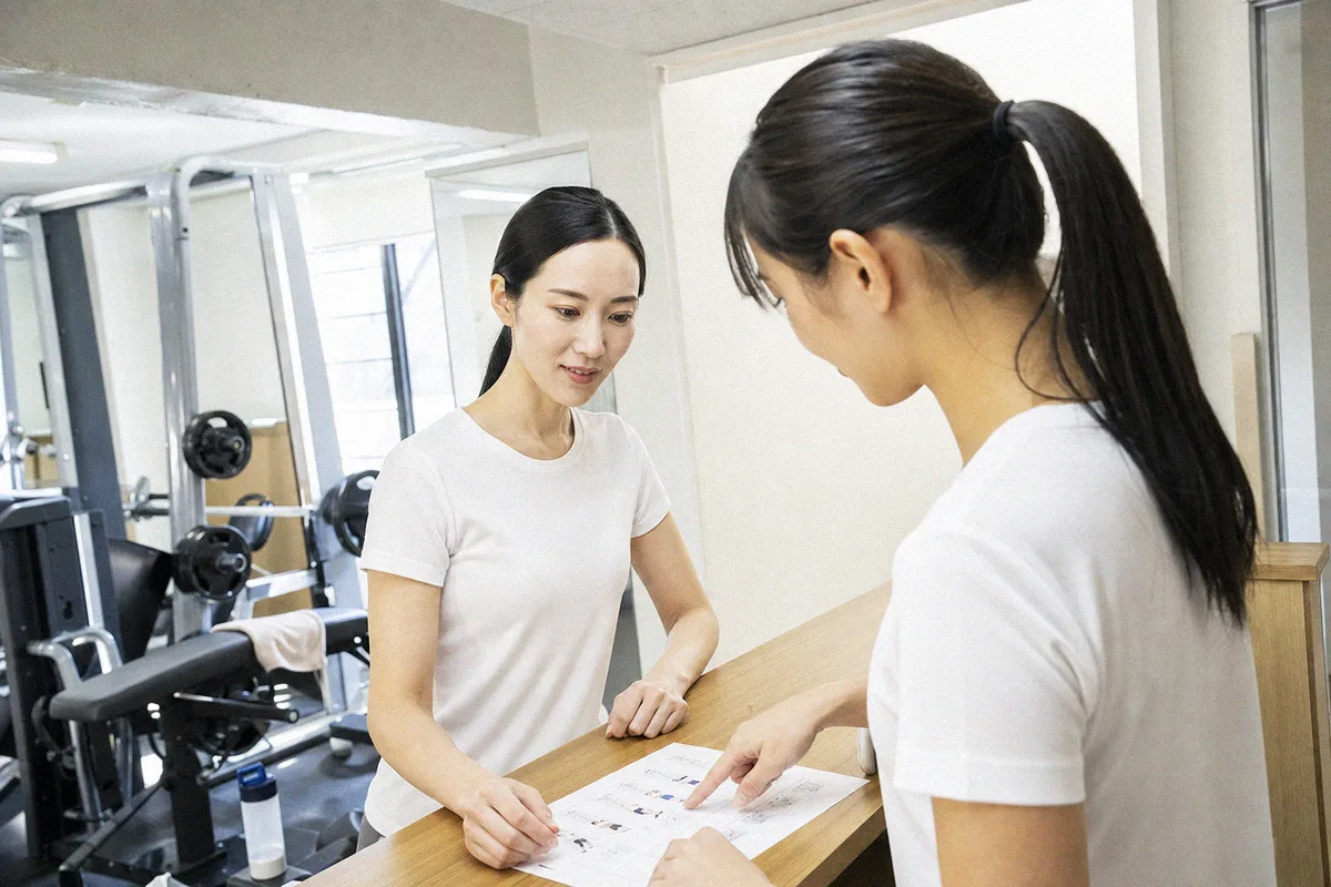 テーブル越しに料金や進め方について話すトレーナーと利用者