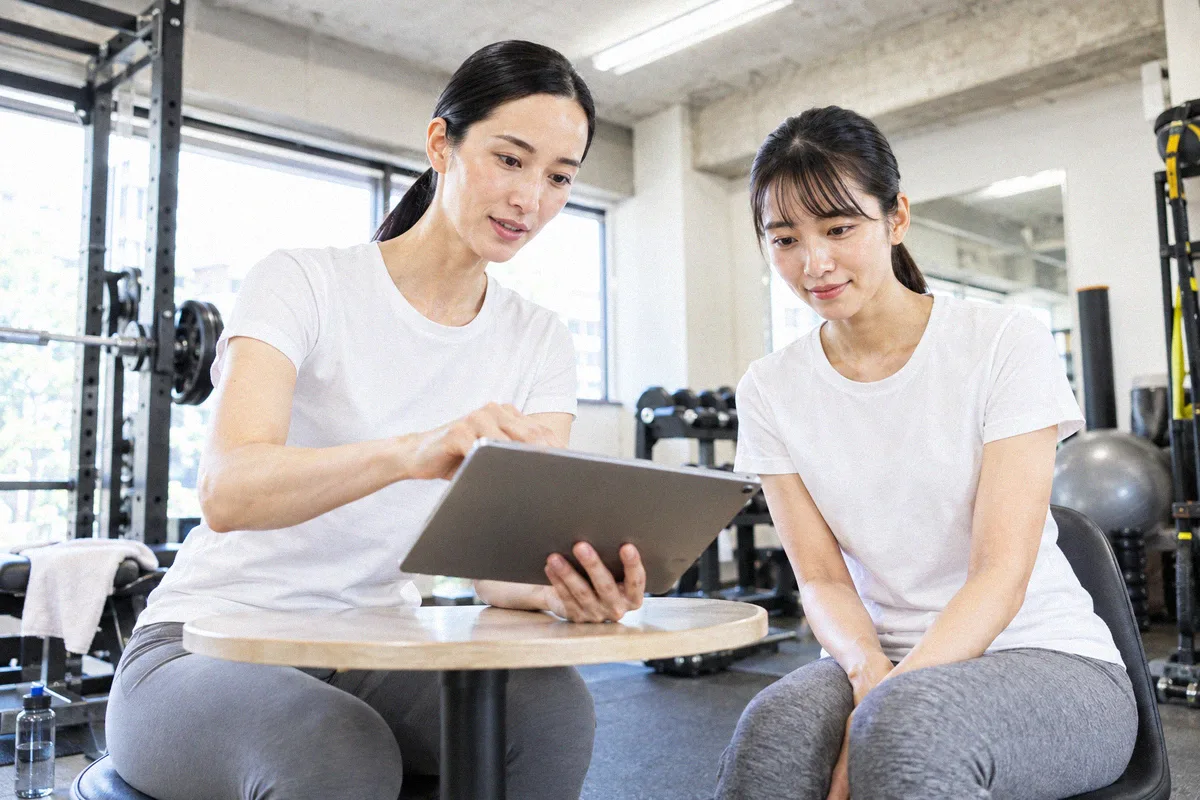 タブレットを見ながらトレーニング計画の説明を受ける利用者とトレーナー