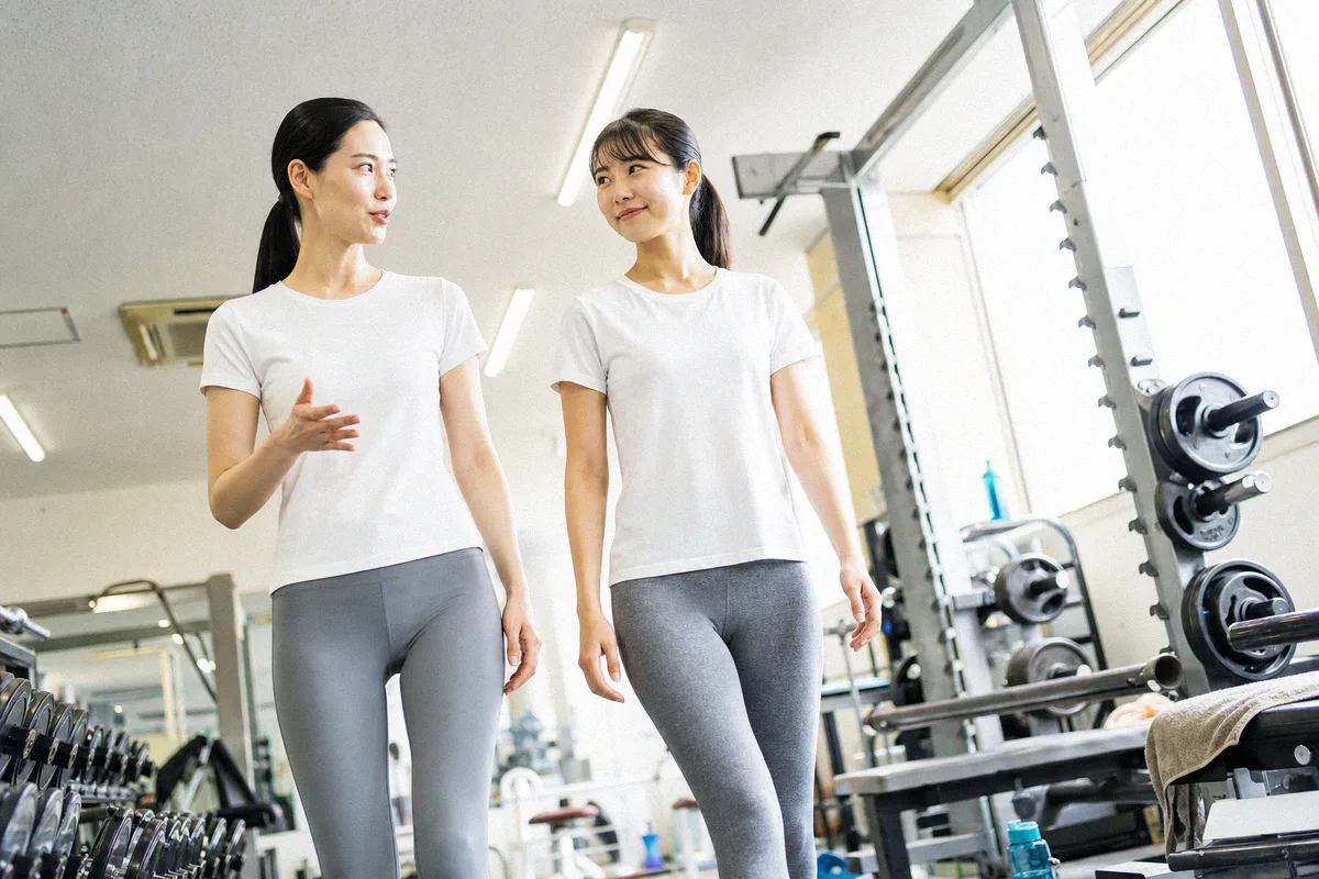 フロアを並んで歩きながら話すトレーナーと利用者