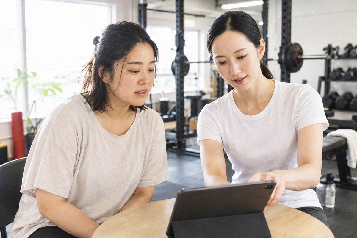 タブレットを見ながらトレーニング計画の説明を受ける利用者とトレーナー